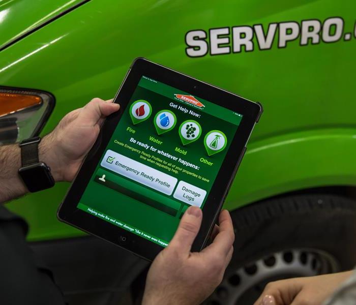Hands holding an IPad with SERVPRO app