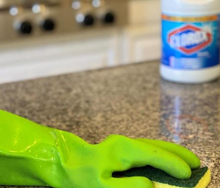 Green cleaning glove with a sponge and Clorox bleach.